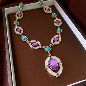 Macro shot of vintage style gold-plated necklace with purple gemstones and turquoise details