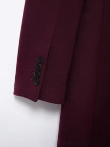 Gros plan du poignet d'un manteau en laine bordeaux avec quatre boutons noirs et sergé