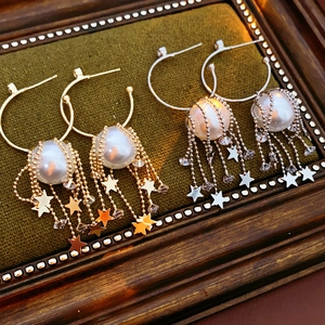 Vue détaillée de boucles d'oreilles étoiles dorées et argentées avec perles sur un plateau