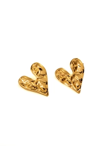 Detailed view of golden heart-shaped stud earrings with unique hammered metal texture