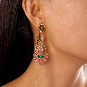 Macro shot of vintage gold flower earrings with teardrop faux gemstones worn on a model