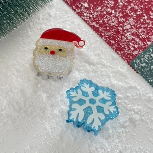 Detailed view of Santa Claus and snowflake hair clips on a festive snow-themed background