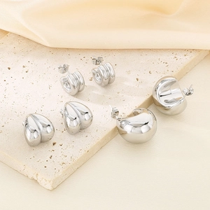 Gros plan de boucles d'oreilles argentées en forme de C et de cœur sur soie