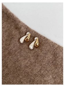 Macro detail of two-tone teardrop earrings showing gold polish and silver matte textures