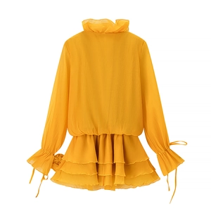 Detail of ginger yellow chiffon top showing high-neck ruffles and layered hem design