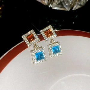 Détail de boucles d'oreilles carrées bleues et ambre avec sertissage halo brillant