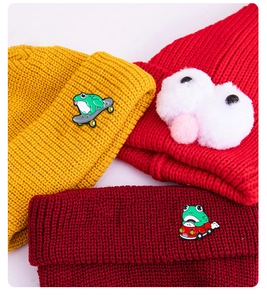 Detailed view of colorful knit hats with creative green frog enamel pins and cute accents