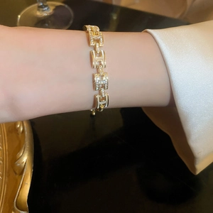 Détail macro du bracelet à maillons H dorés avec émail blanc et oxydes de zirconium