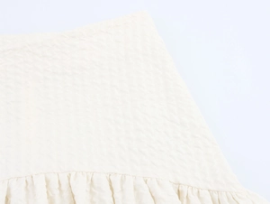 Détail du tissu seersucker blanc cassé avec une bordure à volants élégante et texturée