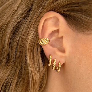 Ensemble de boucles d'oreilles et bagues d'oreille dorées à tissage croisé sur un mannequin