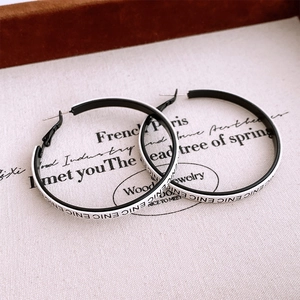 Detail of round hoop earrings with black and white color block and ENIC letter pattern