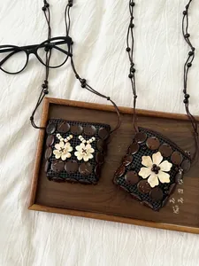 Detail of handcrafted bohemian coconut shell mini bags with daisy wood carvings