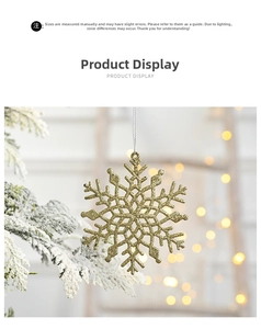 Golden glitter snowflake ornament hanging on a snowy Christmas tree branch with bokeh lights