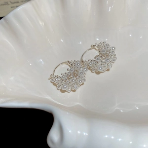 Close-up of cluster pearl U-shaped earrings on a decorative white shell porcelain plate
