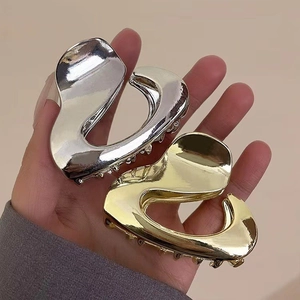 Macro shot of gold and silver irregular streamlined metal hair claws in hand