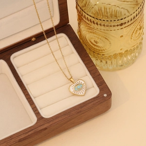 Detail of gold heart pendant with blue evil eye enamel in a wooden jewelry box
