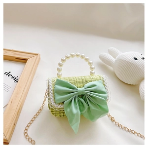 Close-up of green tweed bag featuring a large satin bow and elegant pearl handle