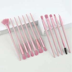 Detail of 12-piece pink makeup brush set with soft fiber bristles on white geometric props
