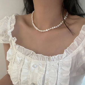Primo piano della collana di perle d'acqua dolce minimalista su modella in abito elegante
