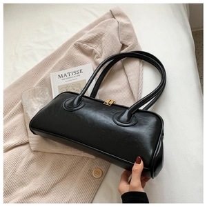 Close-up of black leather handbag with gold hardware on beige corduroy blazer background
