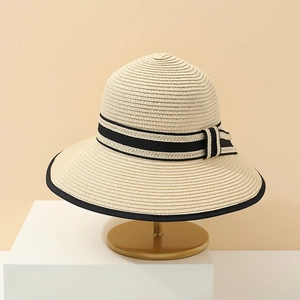 Detailed texture of beige woven straw hat with black stripe ribbon and bow on stand