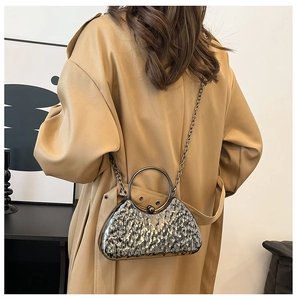 Pochette da sera argento con manico tondo in metallo abbinata a un trench color beige