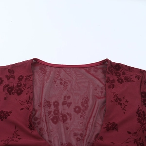 Détail du haut en maille rouge foncé avec motifs floraux floqués et texture du col V