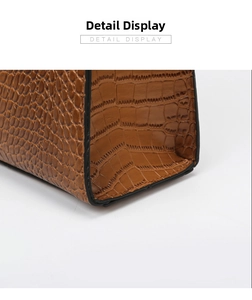 Macro detail of caramel brown faux leather handbag with crocodile pattern and black edges