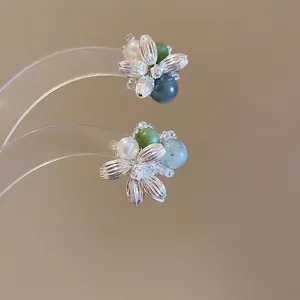 Floral silver needle earrings with white pearls and green agate stones on a grey background