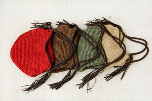 Détail de sacs à bandoulière en paille tressée en quatre couleurs avec de longs glands