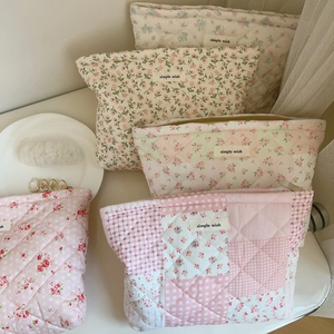 Détail de trousses de maquillage matelassées en coton fleuri avec fermeture éclair