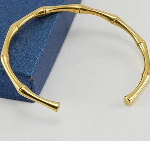 Dettaglio ravvicinato del bracciale rigido a bambù dorato su una confezione blu