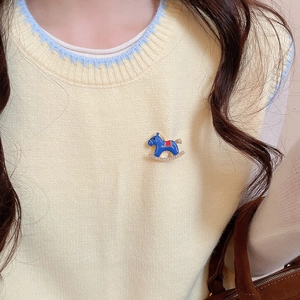 Detailed close-up of blue enamel rocking horse brooch with diamonds on a yellow sweater