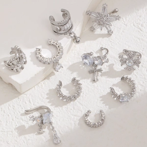Silver zirconia ear cuffs set featuring cross, star, and butterfly tassels on white pedestal