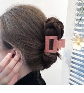 Pink marble acrylic rectangle hair claw clip worn on wavy hair for a stylish look