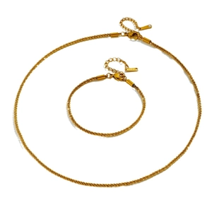 Sparkling gold-plated stainless steel necklace and bracelet jewelry set on white background