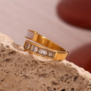 Detail of 18K gold plated cross geometric ring with white shell and inlaid crystals
