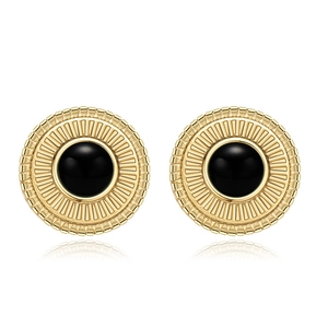 Detail view of round gold starburst earrings with black stone inlay and ribbed texture