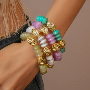Close-up of layered acrylic beaded bracelet with irregular gold accents on wrist