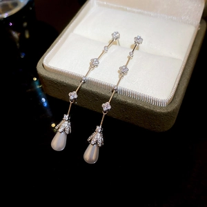 Close-up of long tassel earrings featuring zircon flower links and teardrop pearl charms