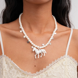 Détail du collier de perles avec pendentif cheval blanc et étoiles argentées sur modèle