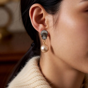 Detail of vintage gold pearl earrings featuring black onyx inlay and sparkling zircons