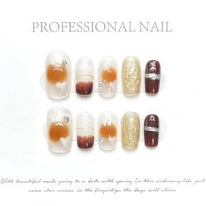 Detail of luxury press-on nails featuring amber marble, gold 3D relief, and red cat eye effect