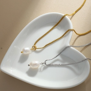 Detail of gold and silver layered necklaces with freshwater pearl pendants in a heart dish