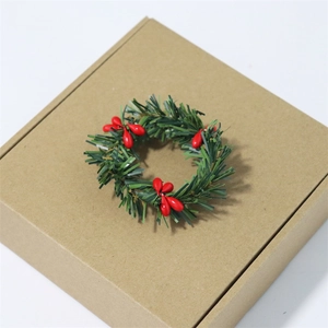 Mini Christmas wreath with green pine needles and red berries on kraft paper box