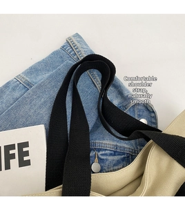 Close-up of durable black wide webbing shoulder strap on a beige canvas tote bag