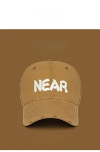 Detailed view of NEAR 3D embroidery on brown distressed baseball cap with ripped brim