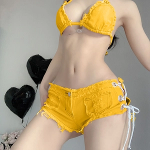 Dettaglio degli shorts in denim giallo a vita alta con frange e top a fascia abbinato