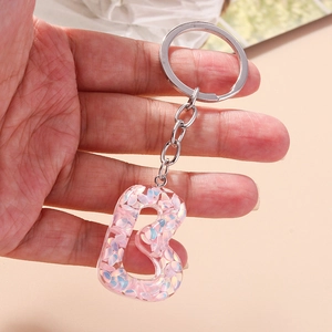 Detail of letter B keychain made of clear resin with iridescent sequins and silver ring
