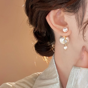 Close-up of elegant pearl drop earrings with sparkling zircon and gold accents on model